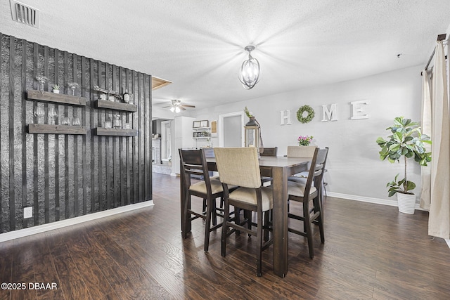 dining area featuring wood finished floors, visible vents, baseboards, a textured ceiling, and ceiling fan with notable chandelier