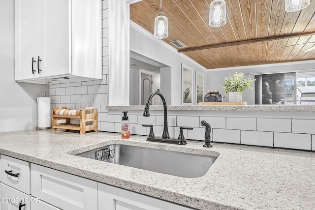 kitchen with a sink, decorative backsplash, wood ceiling, white cabinets, and ornamental molding