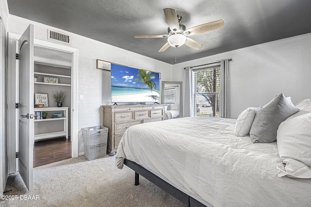 bedroom with a textured ceiling, visible vents, carpet, ceiling fan, and crown molding