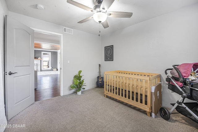 bedroom with a ceiling fan, carpet flooring, a crib, and visible vents