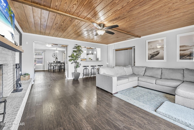 living room with crown molding, wood finished floors, wood ceiling, ceiling fan, and a brick fireplace