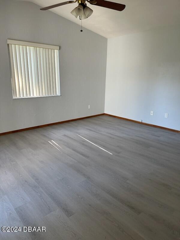 empty room with hardwood / wood-style floors, vaulted ceiling, and ceiling fan