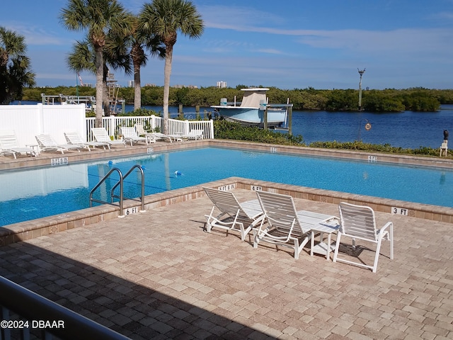 view of swimming pool with a patio area and a water view