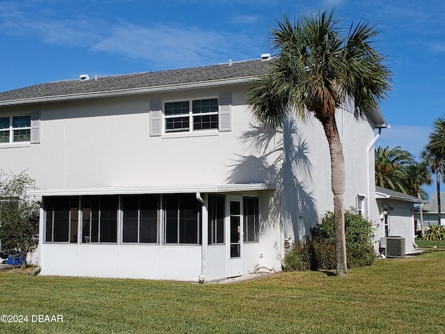 rear view of property featuring cooling unit and a lawn