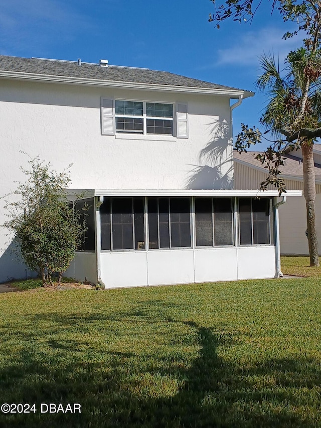 rear view of property with a sunroom and a yard