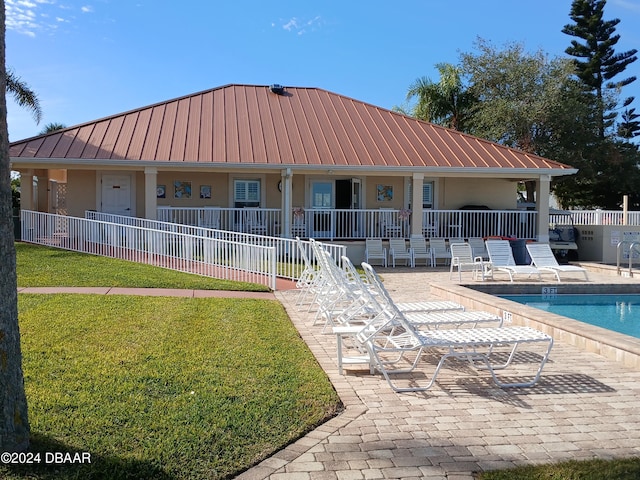 back of property with a lawn, a community pool, and a patio