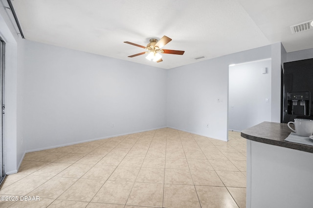 unfurnished room featuring baseboards, light tile patterned flooring, visible vents, and a ceiling fan