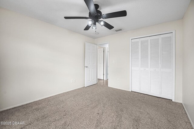 unfurnished bedroom with baseboards, visible vents, ceiling fan, carpet flooring, and a closet