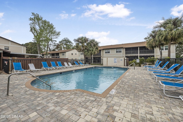 community pool with a patio and fence