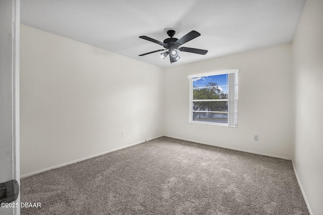 carpeted spare room with a ceiling fan and baseboards