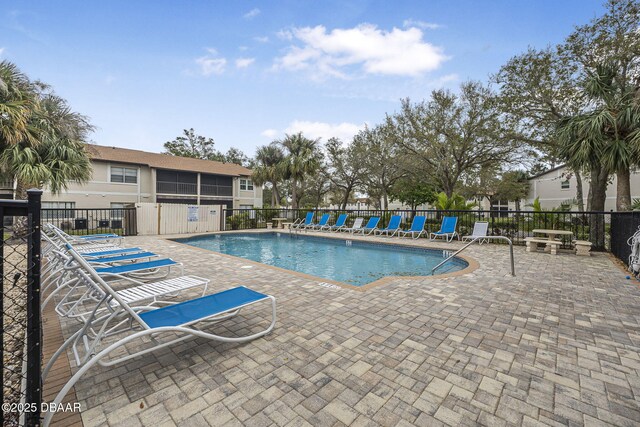 community pool with a patio area and fence