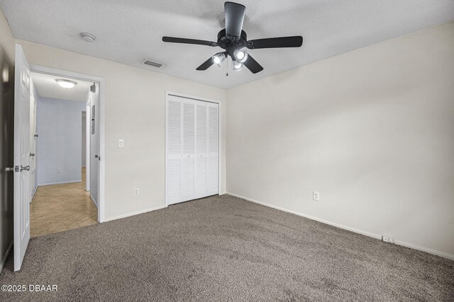 unfurnished bedroom with carpet, a closet, ceiling fan, a textured ceiling, and baseboards