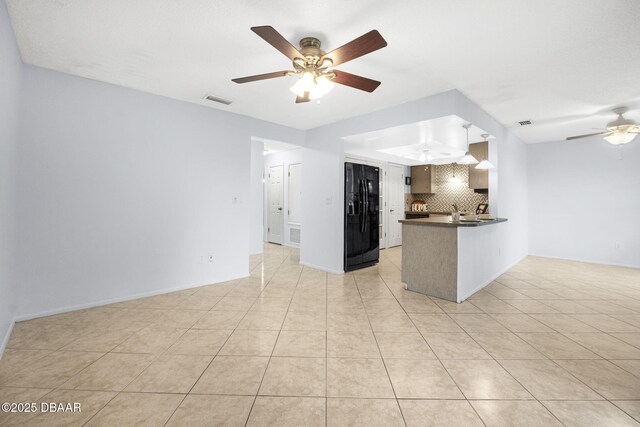 kitchen with open floor plan, tasteful backsplash, dark countertops, and black fridge with ice dispenser