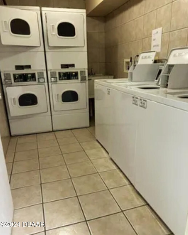 laundry room with washing machine and clothes dryer, light tile patterned floors, and stacked washing maching and dryer