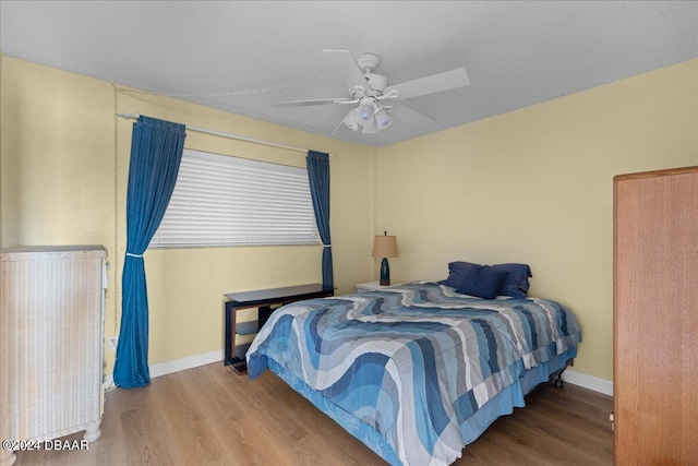 bedroom featuring ceiling fan, hardwood / wood-style floors, and a textured ceiling