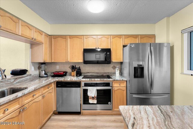 kitchen featuring sink, light stone counters, black appliances, a chandelier, and light brown cabinets