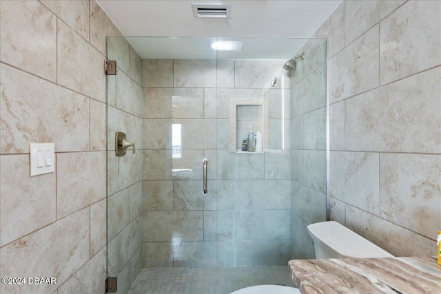 bathroom with a shower with door, tile walls, and toilet