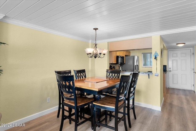 145 N Halifax Ave Unit 707, Daytona Beach, FL 32118 - dining space featuring a chandelier, wood finished floors, baseboards, and ornamental molding