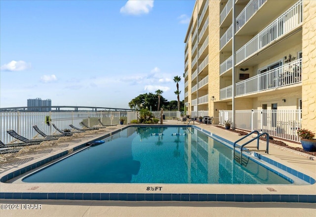 view of pool with a water view and a patio