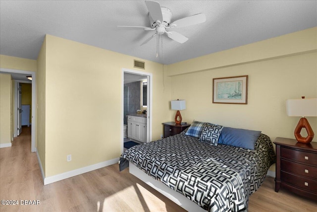 bedroom featuring ensuite bath, a textured ceiling, and light wood-type flooring