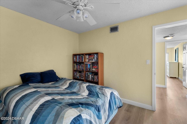 bedroom with ceiling fan, a textured ceiling, and light wood-type flooring