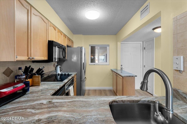 kitchen featuring sink, black appliances, light brown cabinets, a textured ceiling, and light wood-type flooring