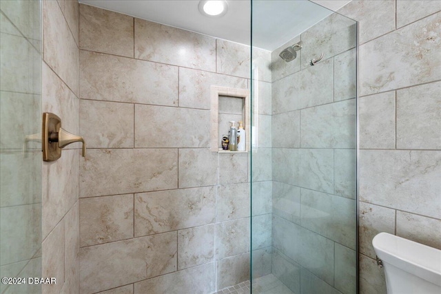 bathroom featuring a tile shower and toilet