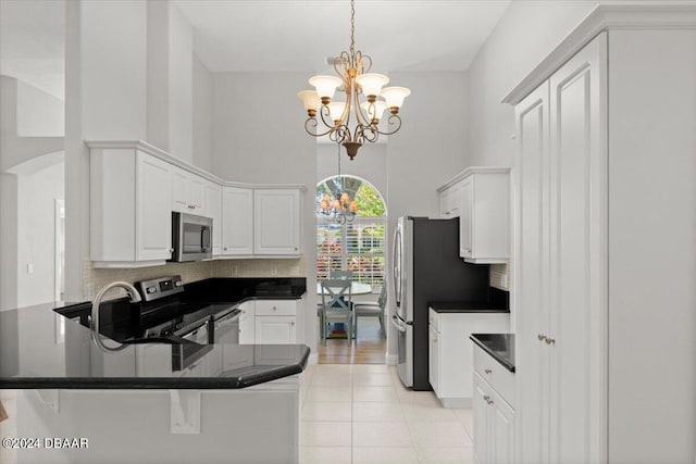 kitchen with stainless steel appliances, pendant lighting, an inviting chandelier, kitchen peninsula, and white cabinetry