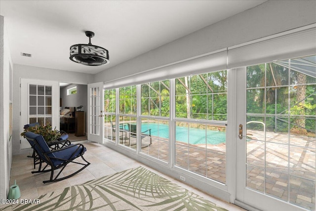 sunroom / solarium featuring french doors and a healthy amount of sunlight