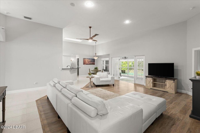 living room with a high ceiling, hardwood / wood-style flooring, and ceiling fan