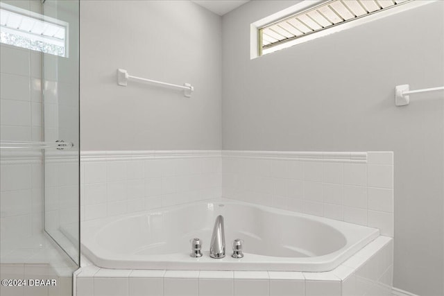 bathroom featuring a healthy amount of sunlight and tiled tub