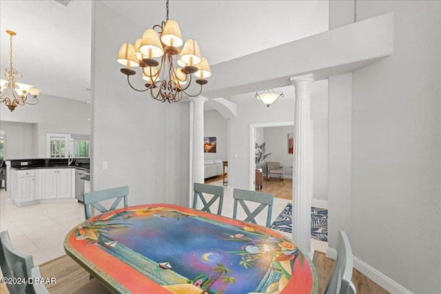 dining room featuring light wood-type flooring, decorative columns, and an inviting chandelier