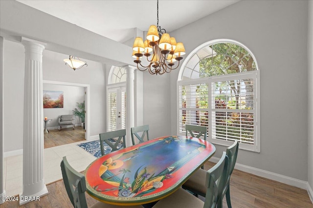 dining room featuring hardwood / wood-style floors, ornate columns, and an inviting chandelier