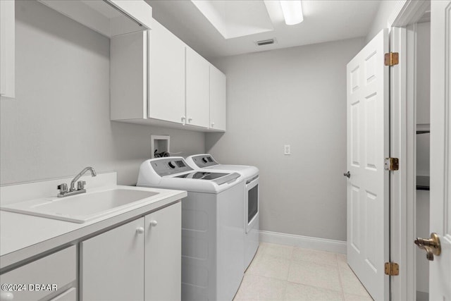 clothes washing area featuring cabinets, sink, and washer and clothes dryer