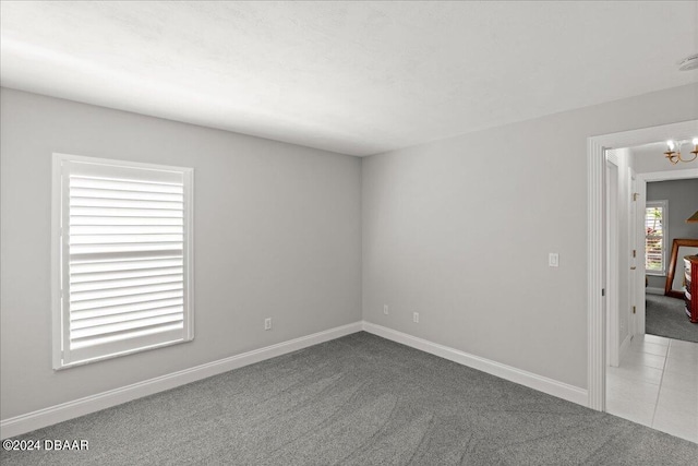 carpeted empty room with a notable chandelier