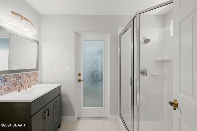 bathroom with tile patterned flooring, a shower with door, vanity, and backsplash