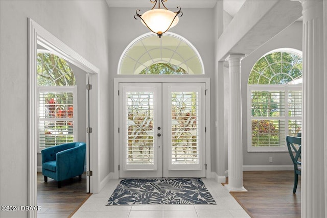 doorway to outside with ornate columns, french doors, hardwood / wood-style floors, and a high ceiling