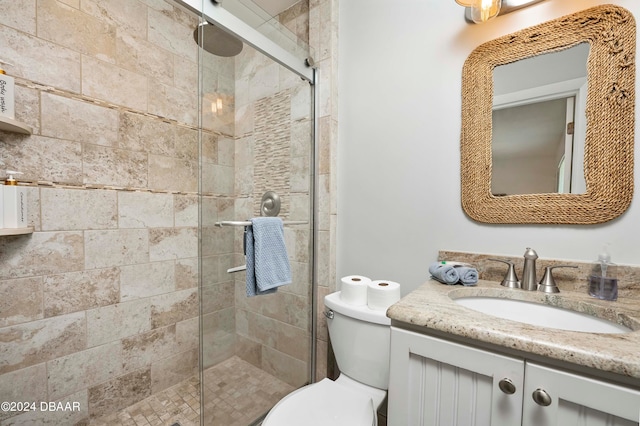 bathroom with a shower with shower door, vanity, and toilet