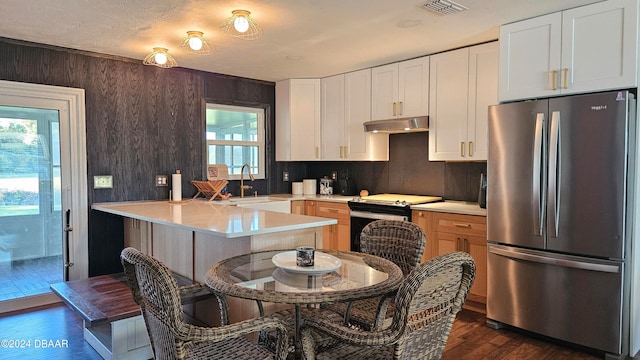 kitchen featuring stainless steel refrigerator, white cabinetry, sink, and a wealth of natural light