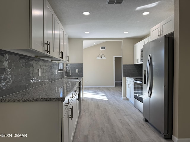 kitchen with a textured ceiling, stainless steel appliances, white cabinets, light hardwood / wood-style floors, and hanging light fixtures