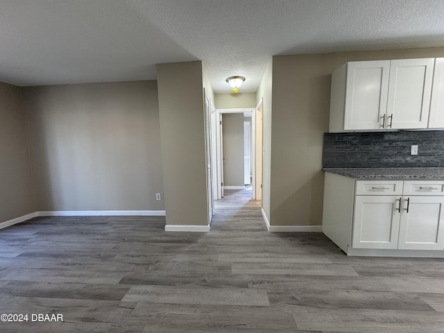 kitchen featuring white cabinets, light wood-type flooring, and backsplash