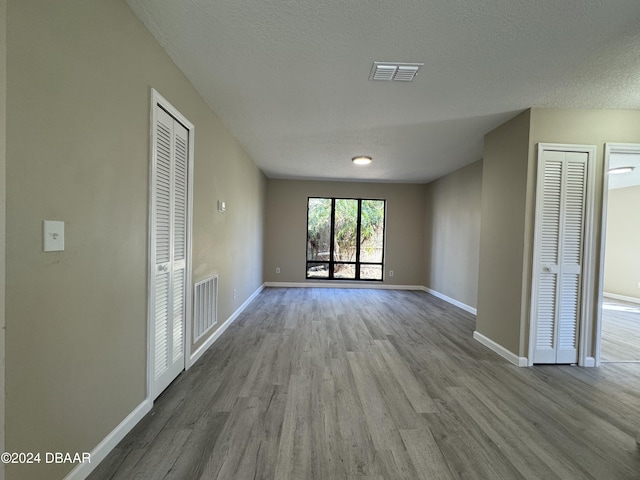 empty room with light hardwood / wood-style floors and a textured ceiling