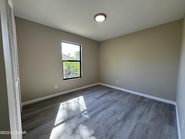 empty room featuring a textured ceiling and dark hardwood / wood-style floors