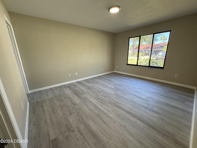 empty room with light hardwood / wood-style flooring and a textured ceiling