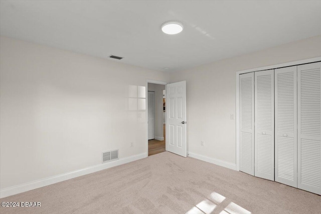 unfurnished bedroom with light colored carpet and a closet