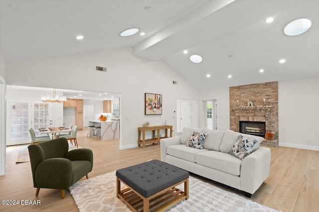 living room featuring high vaulted ceiling, a fireplace, a chandelier, light hardwood / wood-style floors, and beam ceiling