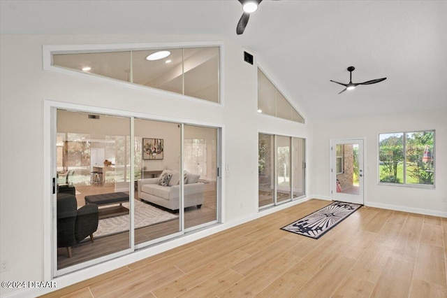 doorway to outside with hardwood / wood-style flooring, high vaulted ceiling, and ceiling fan