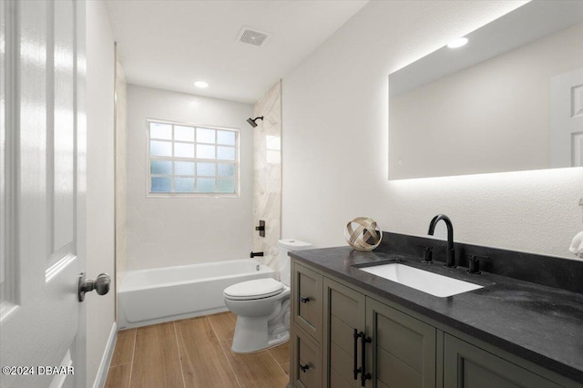 full bathroom with vanity, hardwood / wood-style floors, tiled shower / bath combo, and toilet