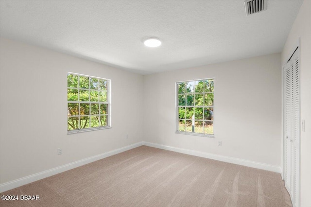 unfurnished bedroom featuring light colored carpet, a closet, and a textured ceiling