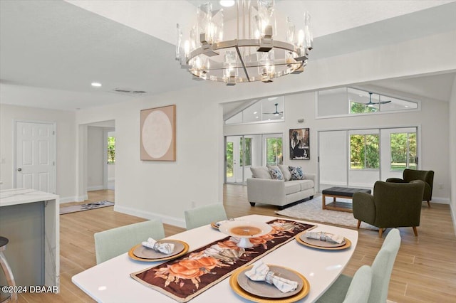 dining area with french doors, lofted ceiling, a healthy amount of sunlight, and light hardwood / wood-style flooring